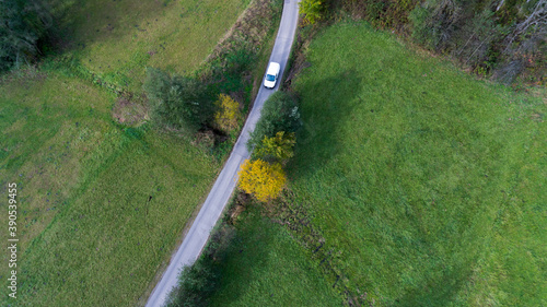 Obraz na płótnie White car driving on an empty road through green fields w salonie