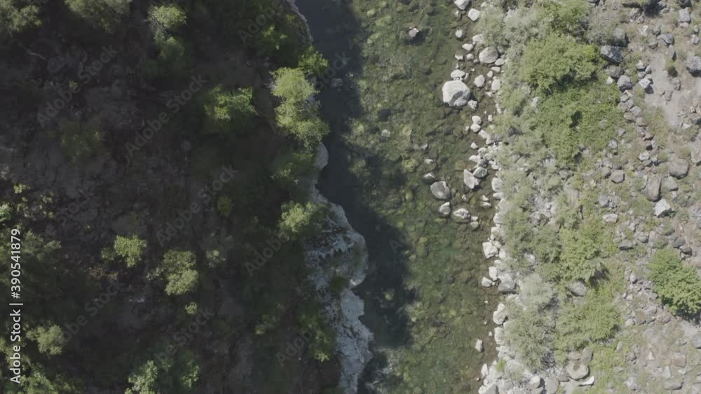 Slow drone flight over a rocky river surrounded by greenery Slow drone flight over a rocky river surrounded by greenery