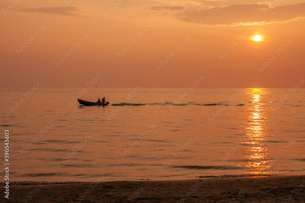 Sunset at the beach and fishing boats pass by