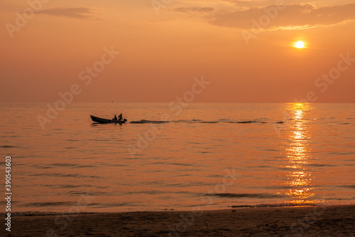 Sunset at the beach and fishing boats pass by