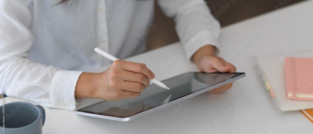 Female hands using tablet on white table with stationery