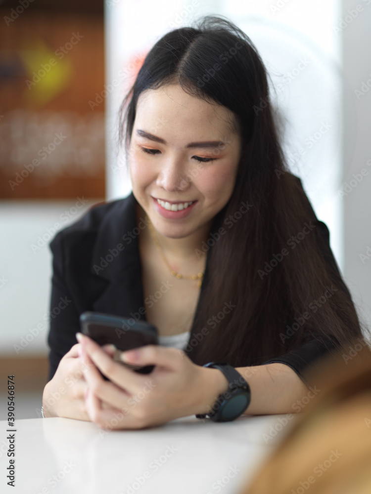Businesswoman texting on smartphone while relaxing in office room Businesswoman texting on smartphone while relaxing in office room