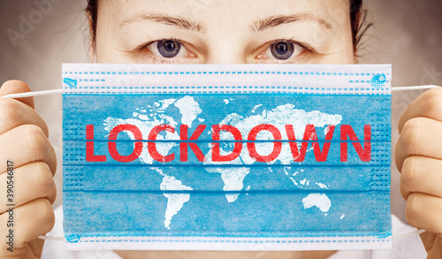 Face mask in hand with inscription LOCKDOWN . Covid-19 outbreak around the world. The global economic crisis. Crash by coronavirus. Life in lockdown around the world photo