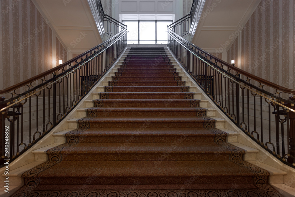 Panoramic view of nice marble stair with carpet and rails leads up 