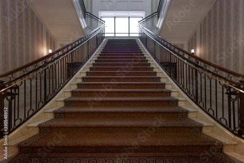 Panoramic view of nice marble stair with carpet and rails leads up 