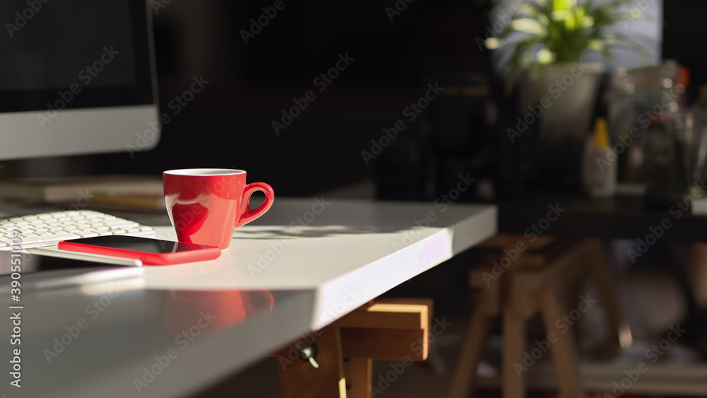 Red coffee cup on computer table with smartphone and supplies Red coffee cup on computer table with smartphone and supplies