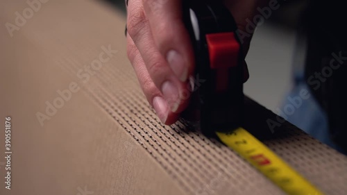A person measures the length of a brown cardboard