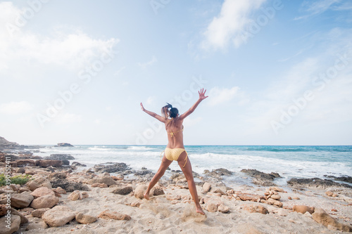 Pretty woman by the sea jumping for happiness