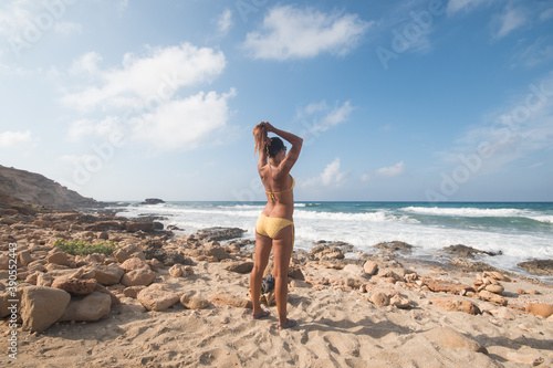 Photography Pretty woman in bikini standing by the sea, preparing to enter the water