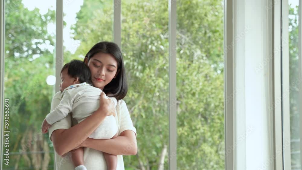 young Asian mother stands holding a child. To lull him to sleep in the living room of the house
young Asian mother stands holding a child. To lull him to sleep in the living room of the house