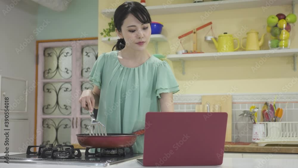 レシピサイトを見ながら料理をしている若い女性 レシピサイトを見ながら料理をしている若い女性