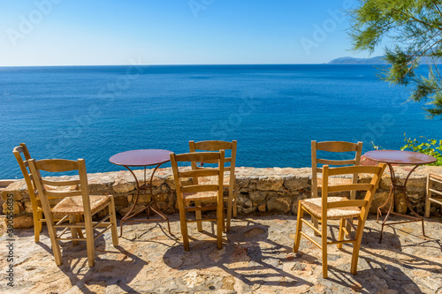 Traditional cafe exterior in the fortified medieval castle of Monemvasia. Iron tables and wooden chairs with the view of the aegean sea in the background.