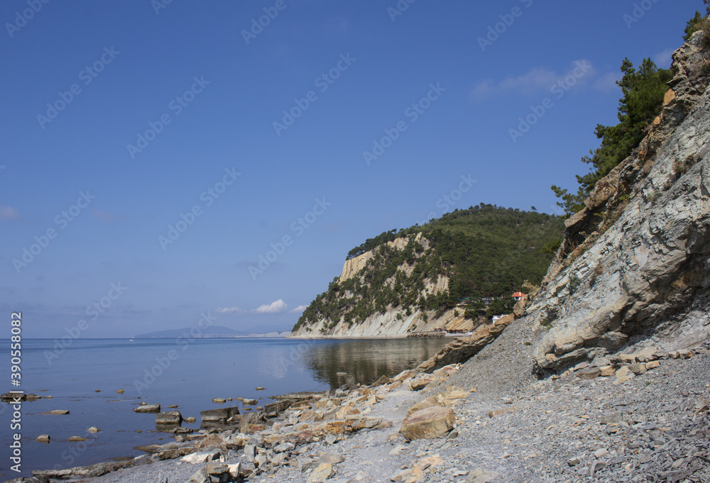 A picturesque landscape of a wild sea beach stretching along the rocks A picturesque landscape of a wild sea beach stretching along the rocks
