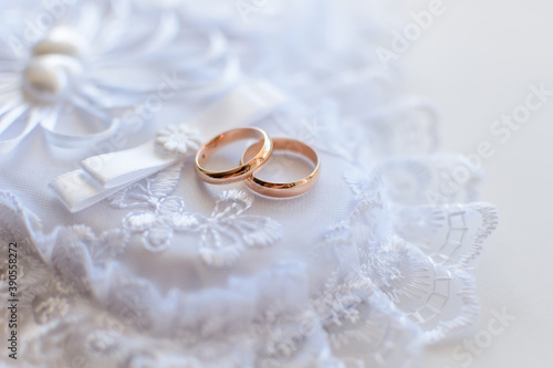 pair of gold wedding traditional rings on a white lace cushion