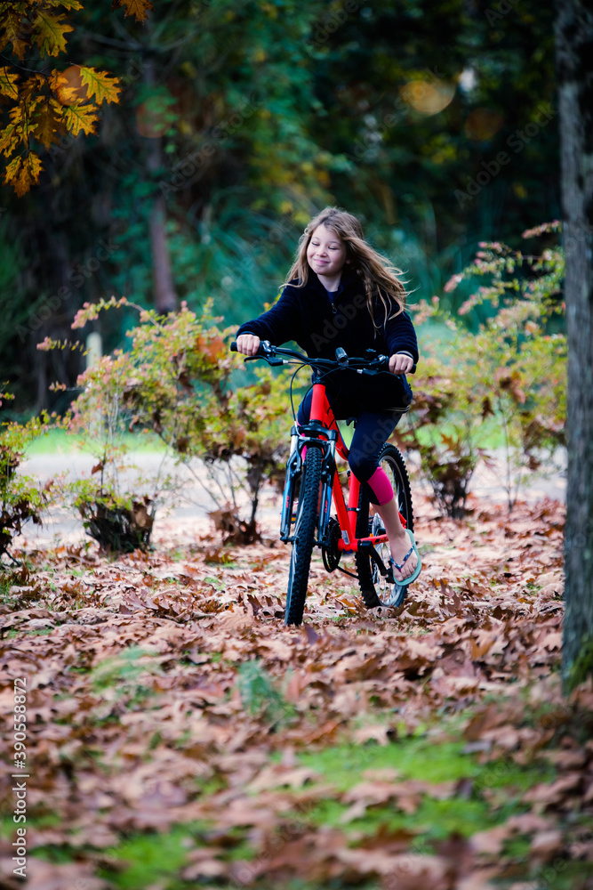 Fototapeta premium cute little girl on her bicycle in the garden or in nature
