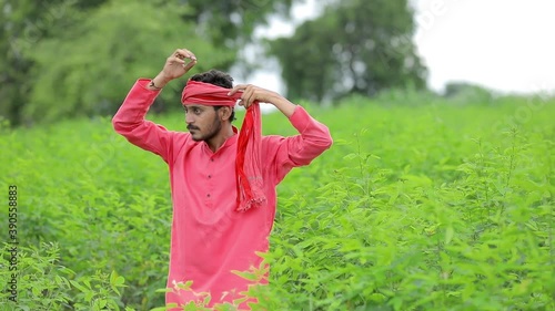 Young indian farmer standing in green pigeon pea field photo