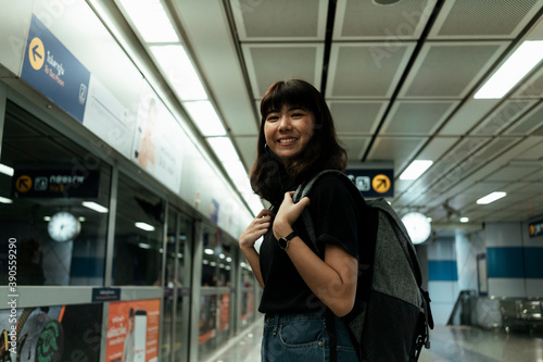 Happy asian woman waiting for a train in metro station.