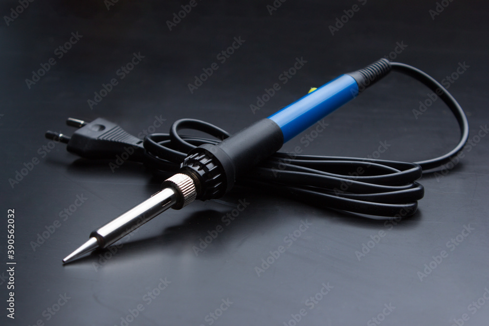 Soldering iron with a blue handle on the old black desktop surface. Soldering iron with a blue handle on the old black desktop surface.