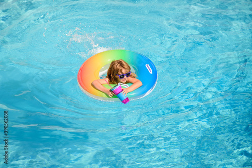 Child in swimming pool on blue water background. Vacation and traveling with kids , copy space. Children play outdoors in summer. Kid with floating ring.