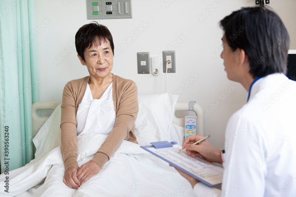 回診に来た医師と会話をする高齢者の女性 回診に来た医師と会話をする高齢者の女性