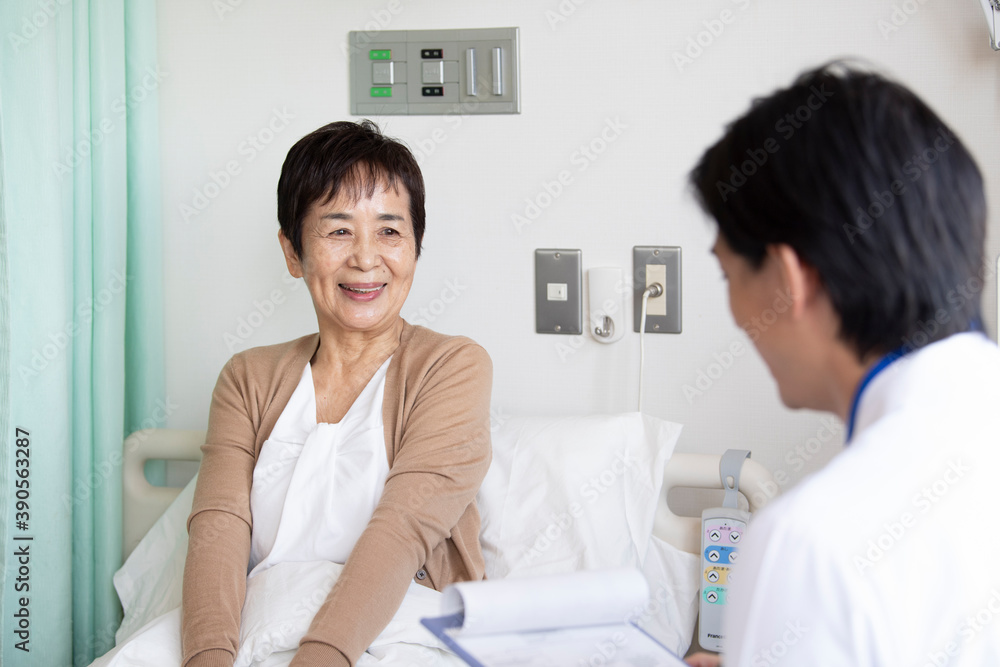 回診に来た医師と会話をする高齢者の女性 回診に来た医師と会話をする高齢者の女性