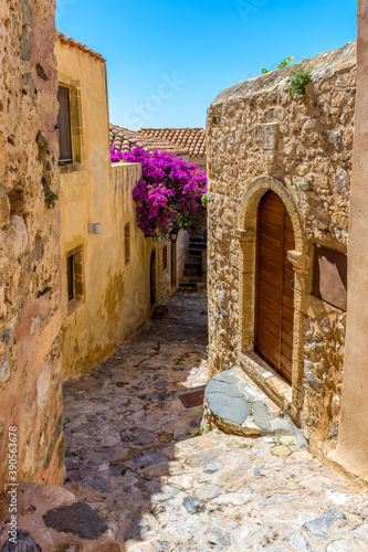 Fototapeta Naklejka Na Ścianę i Meble -  Traditional architecture with  narrow  stone street and a colorfull bougainvillea in  the medieval  castle of Monemvasia, Lakonia, Peloponnese, Greece.