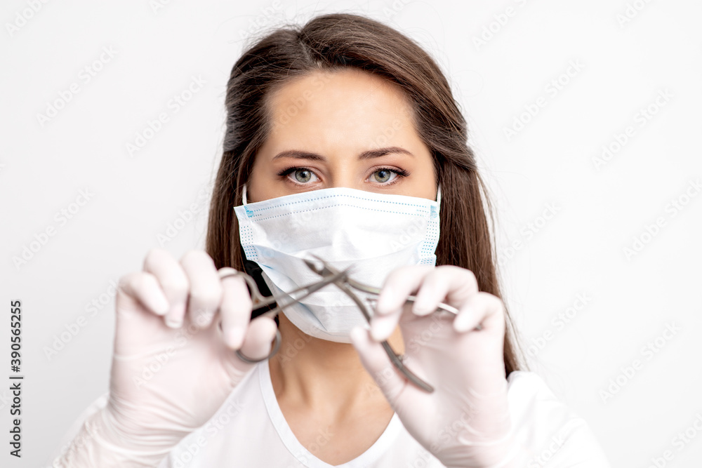 Portrait of manicure master with white protective mask holding manicure tools on white background