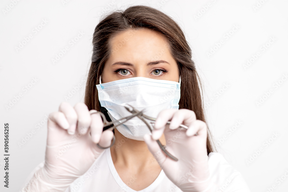 Portrait of manicure master with white protective mask holding manicure tools on white background Portrait of manicure master with white protective mask holding manicure tools on white background