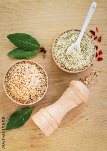 top view of sea salt crystals with spices and herbs additives in a wooden bowl, healthy nutrition, a concept of kitchenware made from natural materials