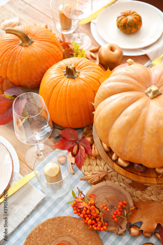 Beautiful table setting with pumpkins and autumn leaves in dining room © Pixel-Shot