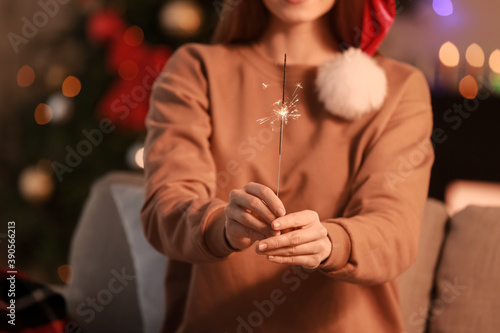 Beautiful young woman with sparkler celebrating Christmas at home