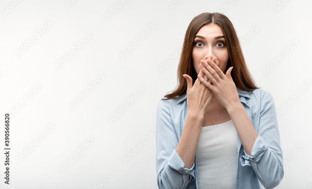 Scared girl is covering mouth with hands on white background. Keep silence concept. Scared girl is covering mouth with hands on white background. Keep silence concept.