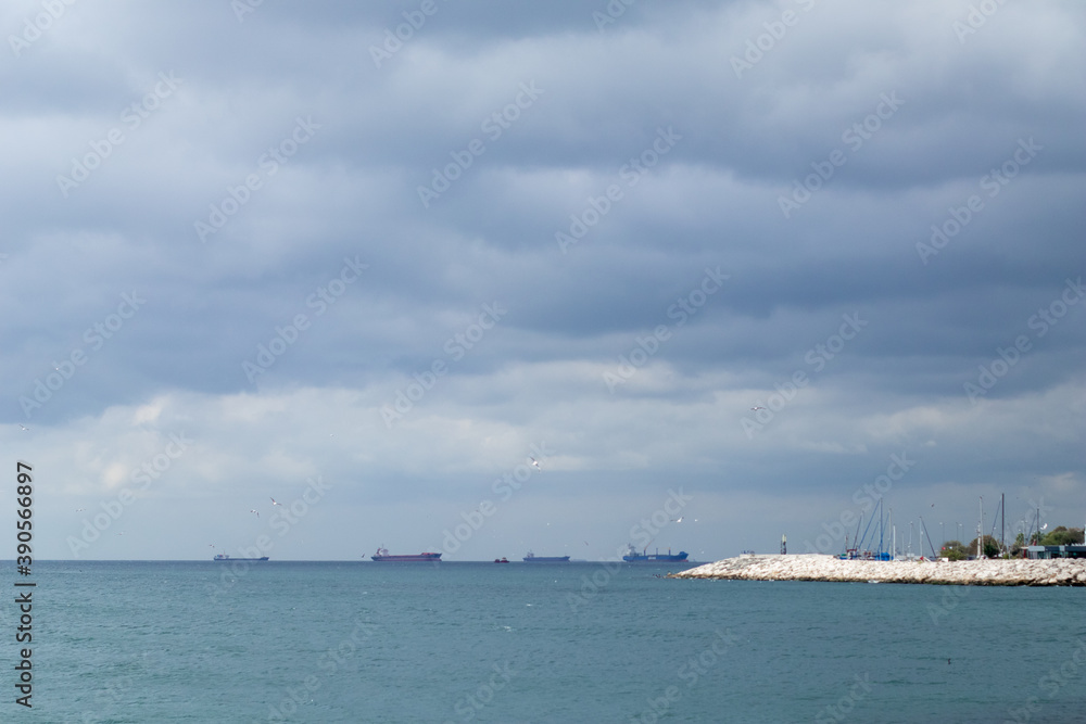 Thunderclouds over the sea. Cargo ships at sea. Stone embankment