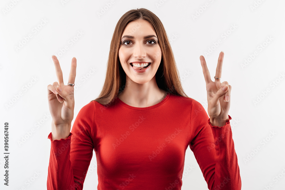 Portrait of a happy young woman with long chestnut hair showing peace gesture Portrait of a happy young woman with long chestnut hair showing peace gesture