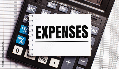 On the table are reports, a calculator and a card with the word EXPENSES on it. Business concept