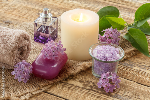 Towel  sea salt  candle and lilac flowers on wooden background.