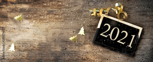 2021 writing on a little board on rustic wooden background with golden confetti and ribbon photo