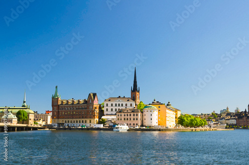 Watercolor drawing of Riddarholmen island district with Riddarholm Church spires and typical sweden colorful gothic buildings, boat ship moored on Lake Malaren water from Kungsholmen, Stockholm