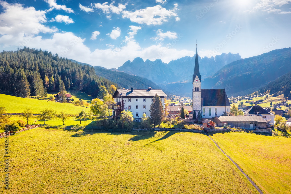 View from flying drone of Pfarramt Catholic Church. Sunny autumn view of Gosau village in the district of Gmunden in Upper Austria, Europe. Traveling concept background.