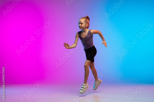 Healthy. Teenage girl, professional runner, jogger in action, motion isolated on gradient pink-blue background in neon light. Concept of sport, movement, energy and dynamic, healthy lifestyle. © master1305