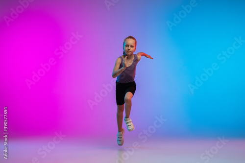 Playful. Teenage girl, professional runner, jogger in action, motion isolated on gradient pink-blue background in neon light. Concept of sport, movement, energy and dynamic, healthy lifestyle.
