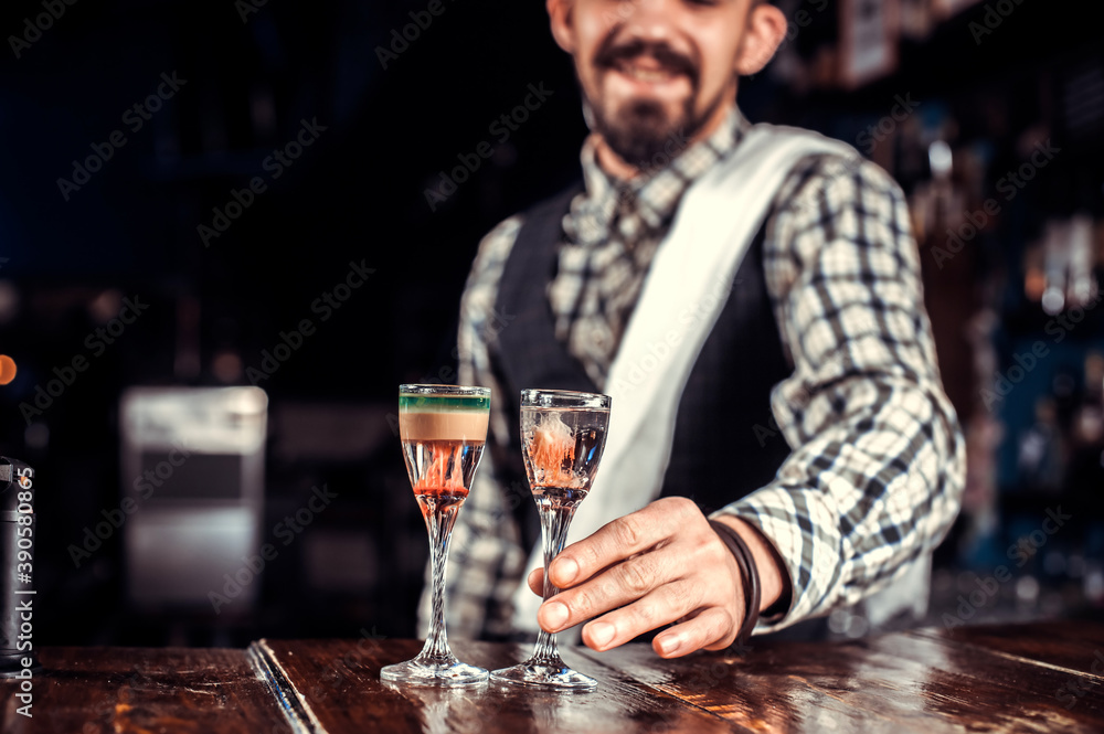 Professional barman decorates colorful concoction while standing near the bar counter in bar