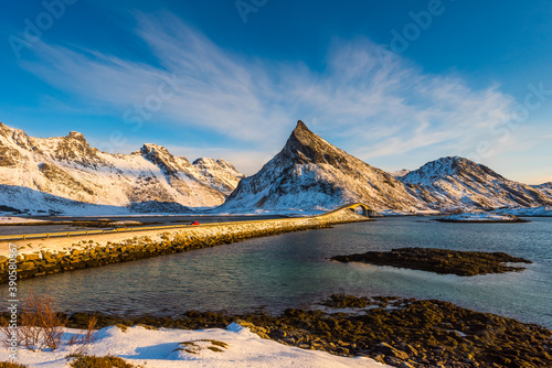 Scenic view over the bridge connecting the village Fredvang with to the Lofoten islands archipelago in Norway in golden sunlight on clear winter day