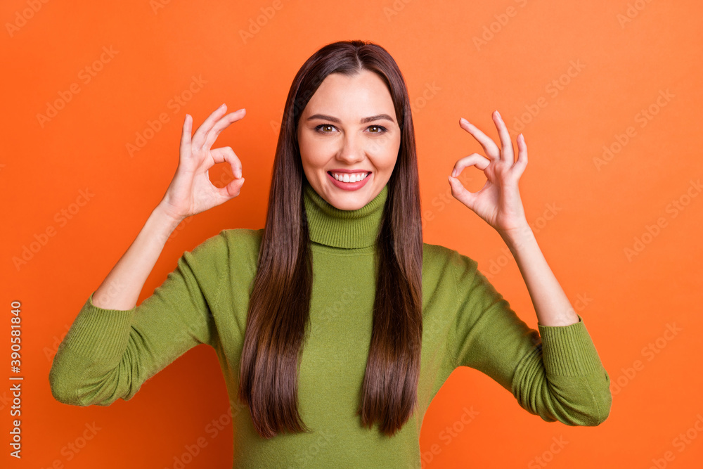Photo of young attractive smiling cheerful positive charming girl showing ok sign isolated on orange color background Photo of young attractive smiling cheerful positive charming girl showing ok sign isolated on orange color background