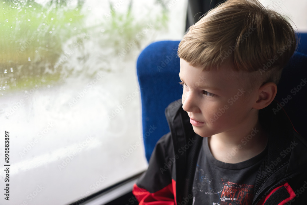 young boy sitting near foggy and misted window in bus or train and looking on raindrops on wet glass young boy sitting near foggy and misted window in bus or train and looking on raindrops on wet glass
