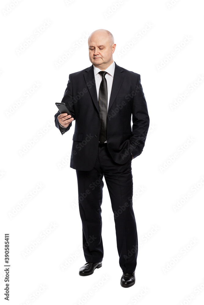 A middle-aged man in a strict black suit looks at the phone. Full height. Isolated on white background. Vertical. A middle-aged man in a strict black suit looks at the phone. Full height. Isolated on white background. Vertical.