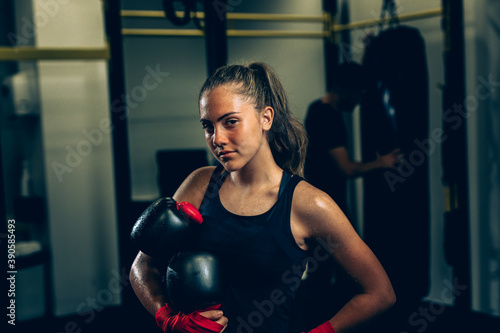 woman holding boxing gloves and posing in gym