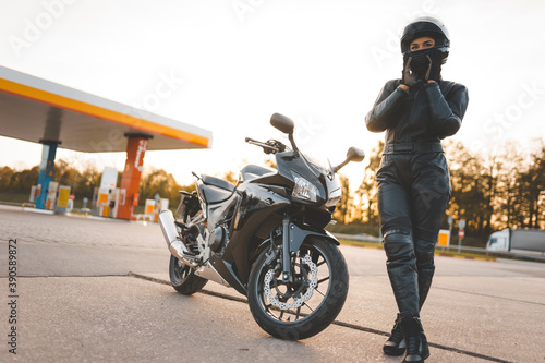Obraz na plátně Brutal biker near motorcycle on the background of a gas station