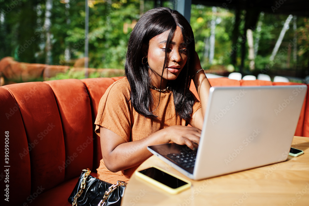 Portrait of beauty young black woman, wear orange outfit, sitting with laptop on office. Portrait of beauty young black woman, wear orange outfit, sitting with laptop on office.