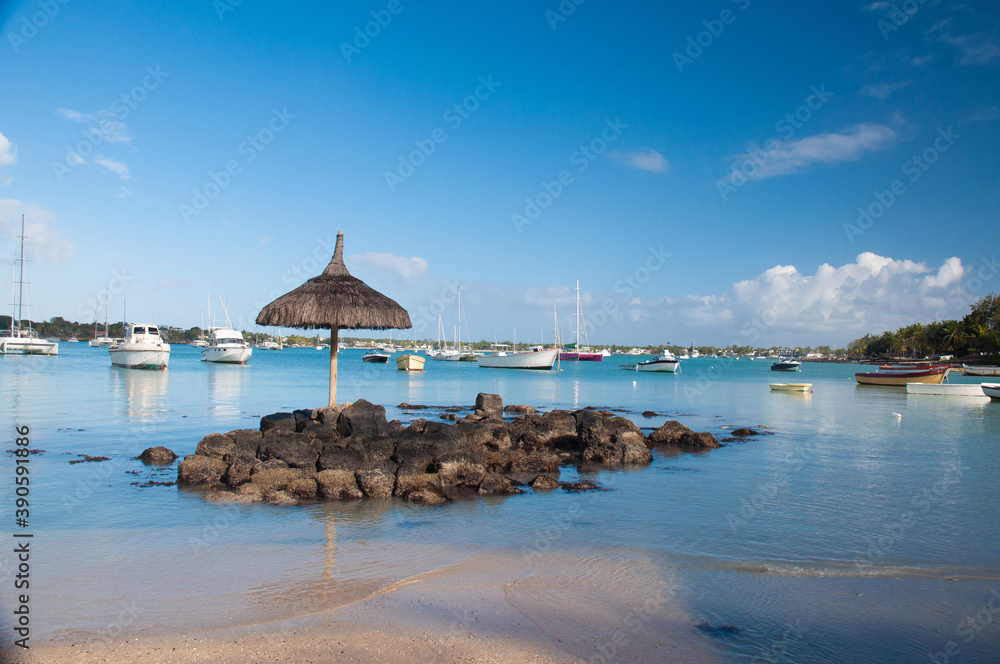 White sand beach with blue water, umbrella and boats